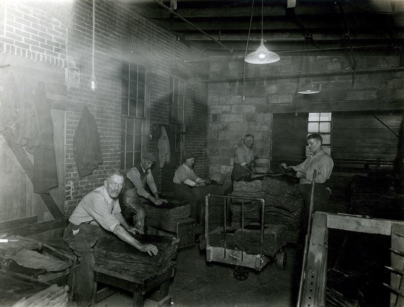 橡胶轮胎工厂内部的黑白照片，一群人在工作